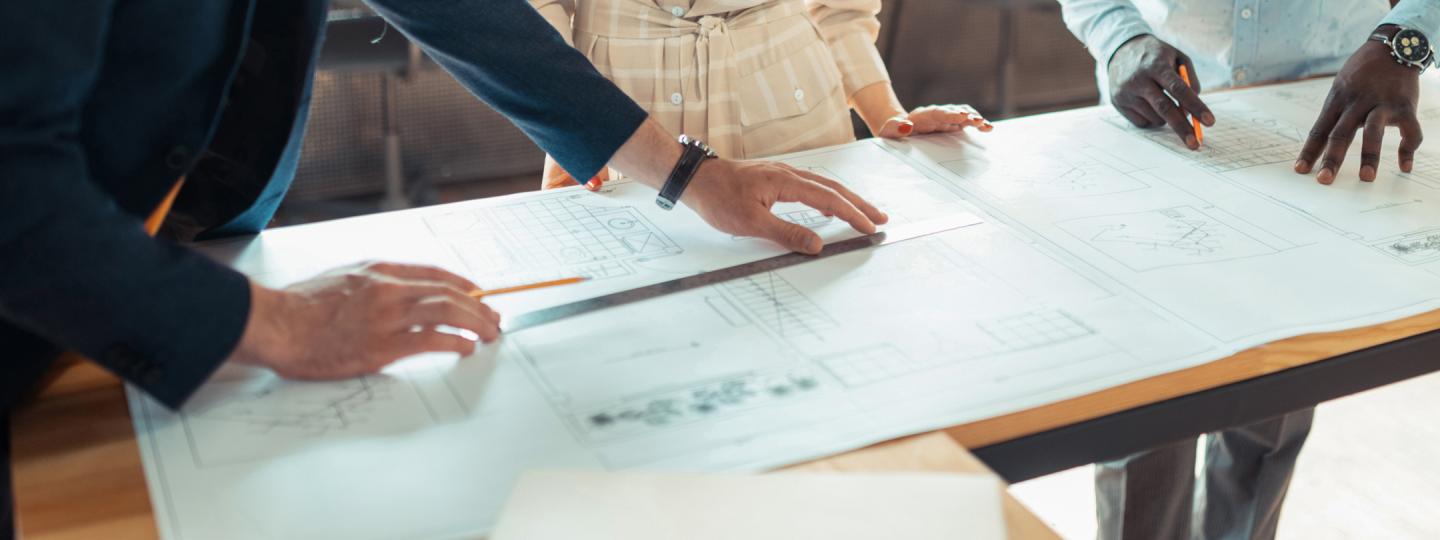 Three sets of hands working on a layout on a table